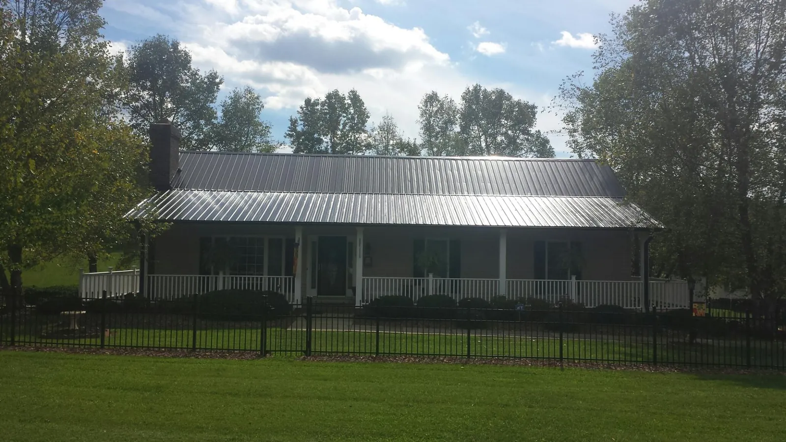 Gray metal roof on a brick ranch with a full width front porch — Gutter Guard Installation work by our crew in New Vienna