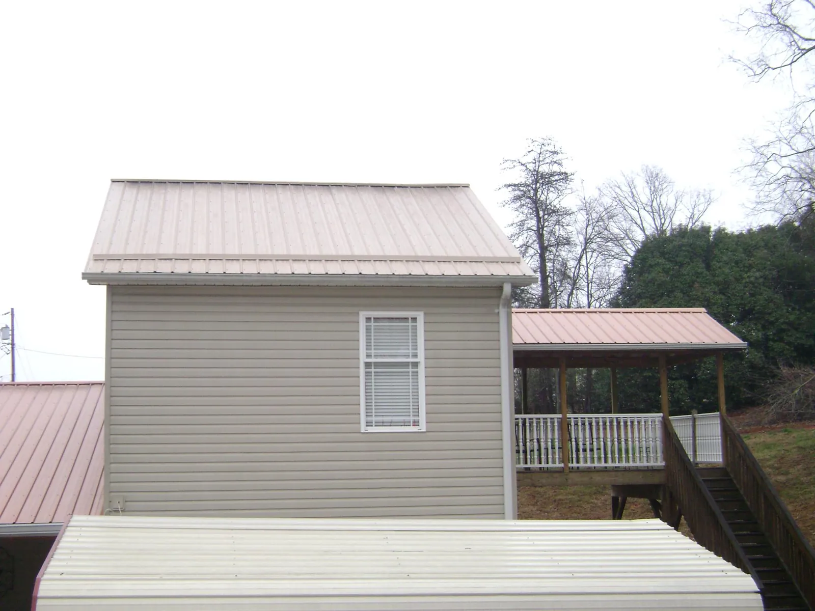 Tan metal roofs on a two story addition and attached porch, from a Roof Replacement job in New Vienna